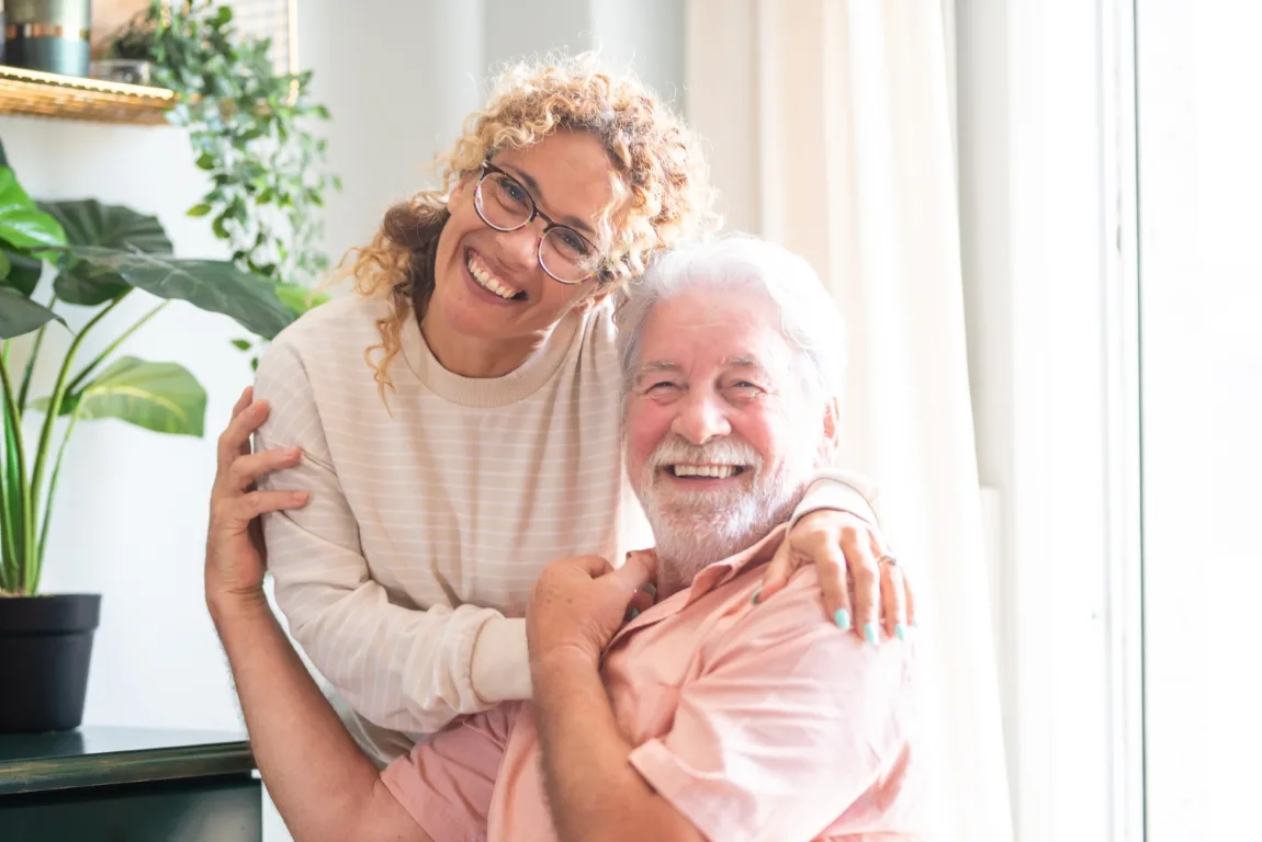 Portrait of happy middle-aged woman and senior father hugging sp