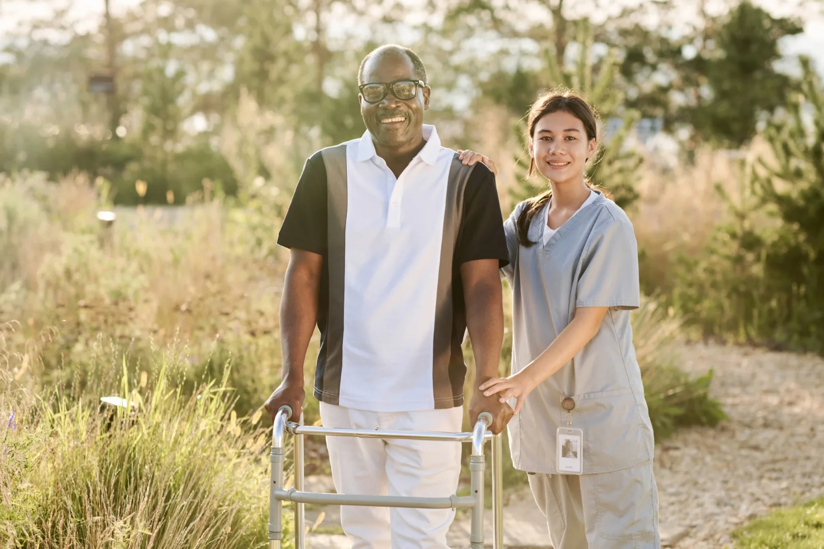 Senior man walking outdoors with nurse